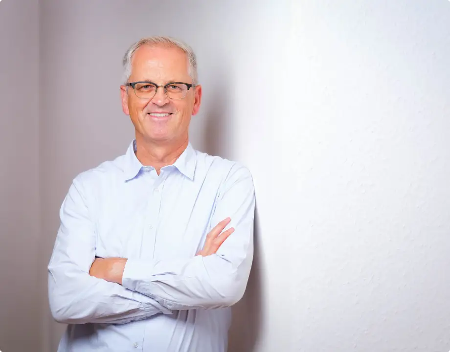 Hinrich Wendroth mit verschränkten Armen vor heller Wand