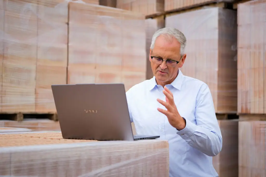 Hinrich Wendroth am Laptop zwischen Paletten mit Ziegelsteinen