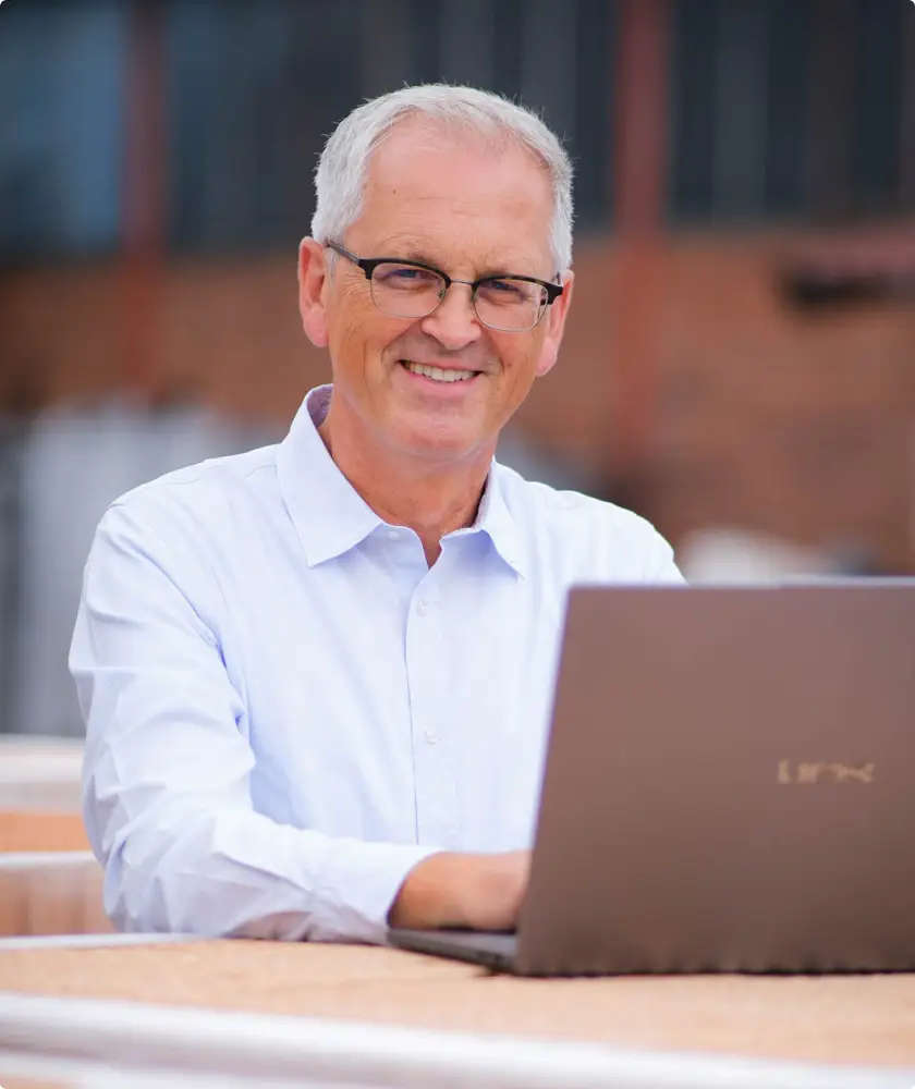 Hinrich Wendroth arbeitet am Laptop vor einer Ziegelwand
